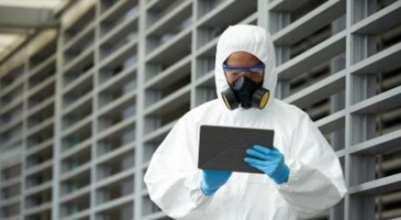 opérateur avec combinaison et masque à gaz réalisant un audit de site avec tablette